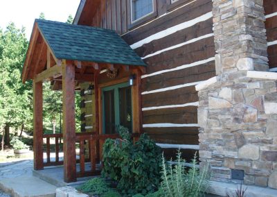 square log home with timber frame entryway